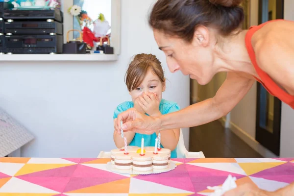 Mulher colocando velas no bolo de festa e criança com emoção expre — Fotografia de Stock