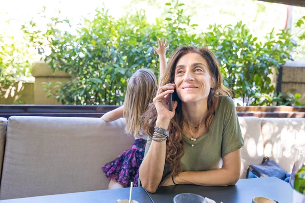 Γυναίκα που μιλάει στο τηλέφωνο στη βεράντα του εστιατορίου δίπλα της daug — Φωτογραφία Αρχείου