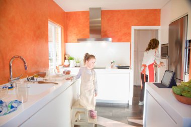 küçük çocuk annesi mutfakta yanındaki tablet bakarak