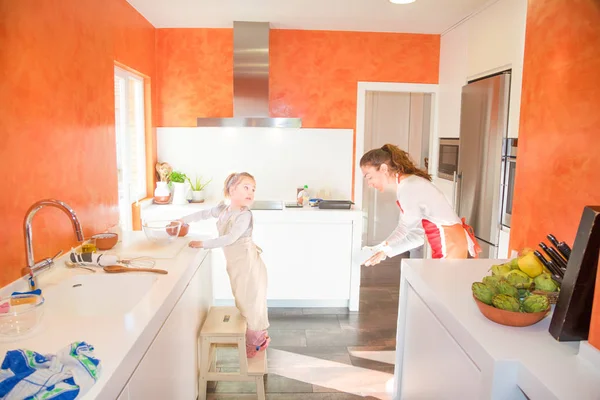 Kind kocht und sieht Mutter in der Küche an — Stockfoto