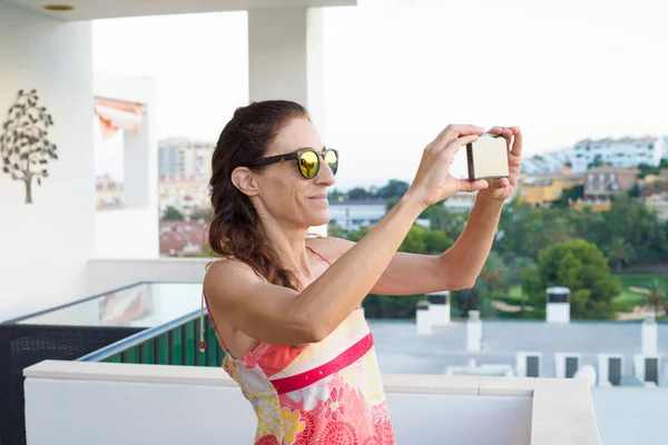 Женщина фотографируется со смартфоном на террасе — стоковое фото