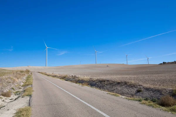 Estrada rural ao lado de turbinas eólicas — Fotografia de Stock