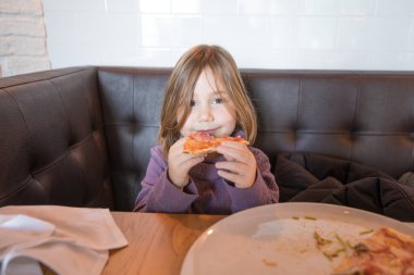 küçük çocuk bakarak ve pizza restoranında yemek