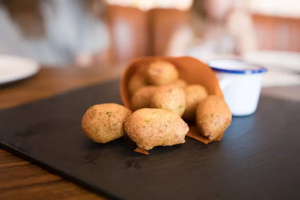 Nahaufnahme von Kroketten in Papierkornett auf schwarzem Tablett — Stockfoto