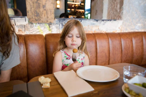 Kleines Mädchen schaut Kroketten in Gabel im Restaurant an — Stockfoto