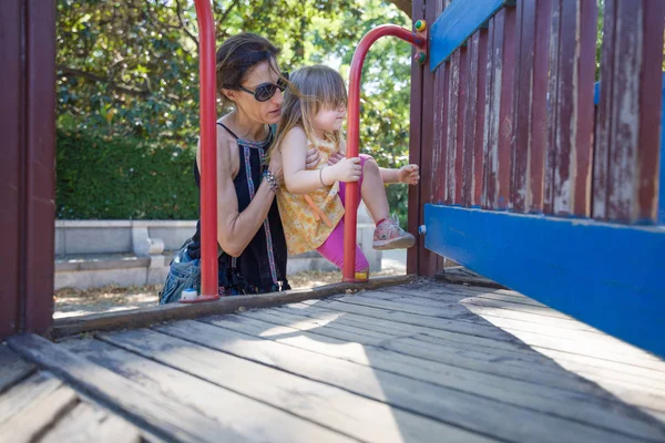 Mother helping girl to climb to the playground — Stock Photo, Image