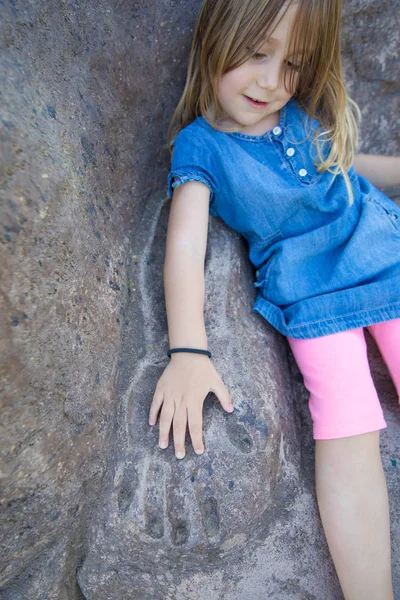 Malá holčička, umístění ruku na plíseň paže do kamene — Stock fotografie
