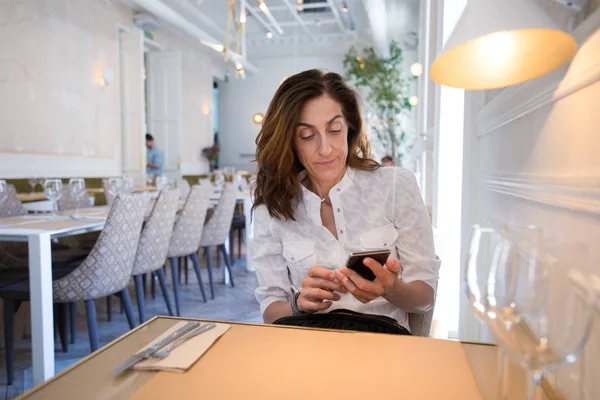 Mujer usando teléfono móvil en restaurante — Foto de Stock