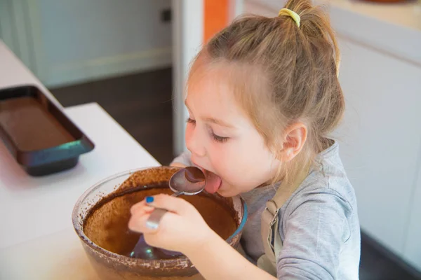 Mädchen probiert geschlagene Schokoladencreme aus Glasschale mit Löffel — Stockfoto