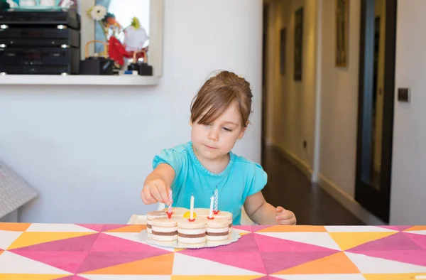 Kleines Kind stellt Kerzen auf Party-Kuchen — Stockfoto