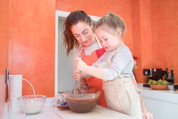 Kleines Mädchen schlägt Schokoladencreme unter Aufsicht der Mutter — Stockfoto