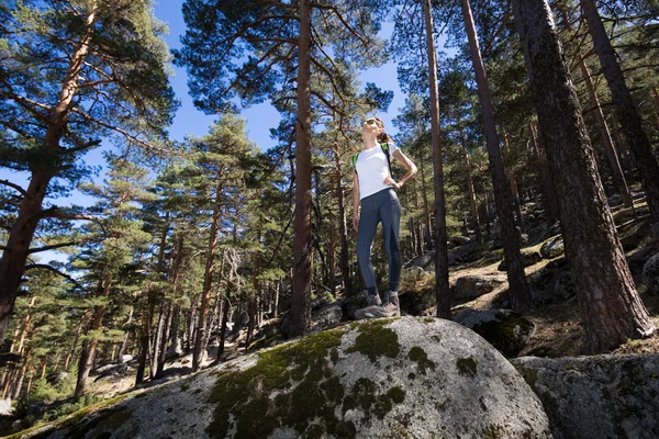 Caminhante mulher posando em uma grande rocha na floresta — Fotografia de Stock