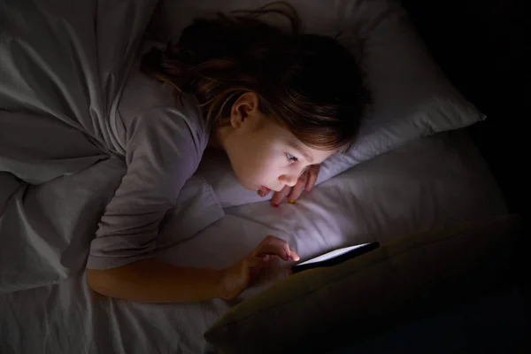 Έξι Ετών Κορίτσι Που Βρίσκεται Στο Κρεβάτι Νύχτα Αγγίζοντας Οθόνη Εικόνα Αρχείου