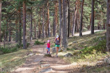 mother and daughter hiking on a trail in forest of Canencia moun