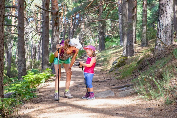 Bergsteigermutter und ihre kleine Tochter lachen auf einem Fußabdruck Stockbild