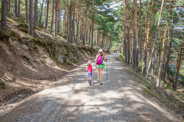 From behind little daughter and mother hiking on a track in fore — Stockfoto