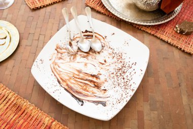 Yemekten sonra üç kaşık boş ve kirli beyaz tabakta.