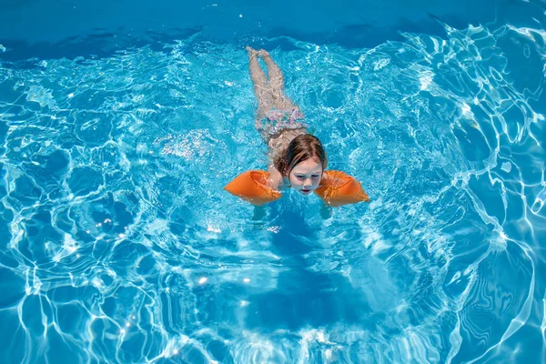 Aerial view child with armbands swimming in transparent blue wat — 스톡 사진