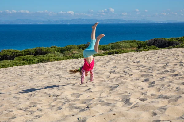 Kleines Mädchen macht Handstand auf Düne mit Afrika am Horizont — Stockfoto