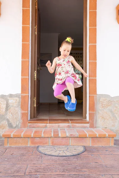 Mała dziewczynka skacze i wystający język — Zdjęcie stockowe