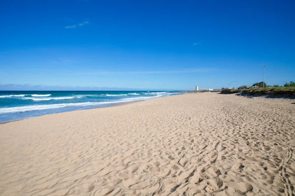 Zand en eenzaam strand van Palmar met oude toren in de horizon — Stockfoto