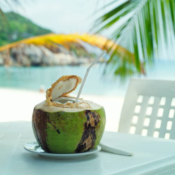 Coconut, beach cafe, on table with blurry background of sea and — Stock Photo, Image