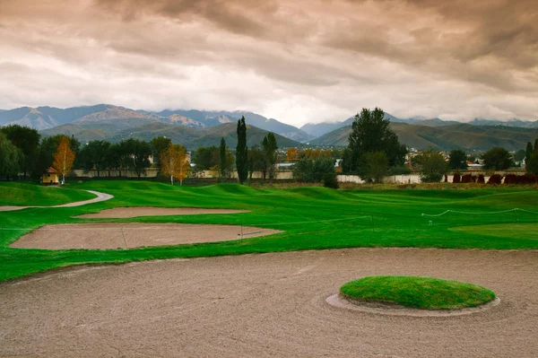 Gioco nel golf club contro le montagne e cielo drammatico — Foto Stock