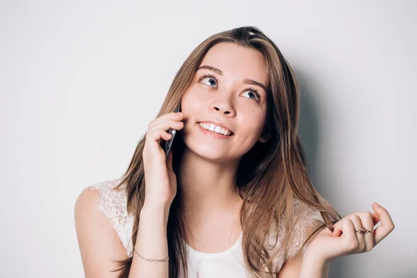 Mujer joven hablando por teléfono sobre un fondo blanco. Una hermosa y divertida chica sonriente —  Fotos de Stock