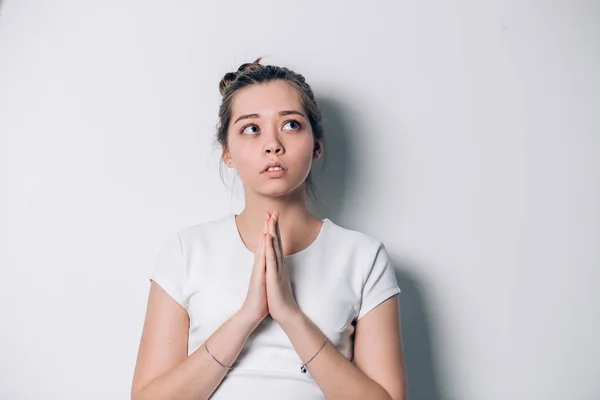 Jovencita rezando. Mujer con las manos dobladas aisladas en blanco mirando hacia arriba con una solicitud — Foto de Stock