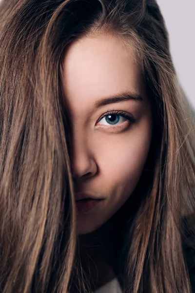 En flicka med blå ögon tittar piercing på kamera, närbild — Stockfoto