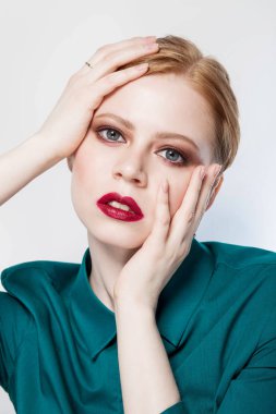 Profesyonel makyaj kırmızı dudaklı beyaz arka plan yakın çekim tutuşup başından iki yanda yeşil gömlekte Kapalı gözlerle güzel kızıl saçlı kız