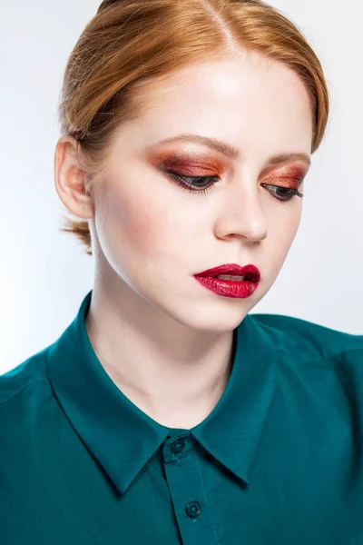 Retrato de close-up de uma linda menina ruiva com maquiagem brilhante em um fundo branco. A mulher olha para baixo. Beleza, cuidados faciais, moda, conceito de pele limpa — Fotografia de Stock