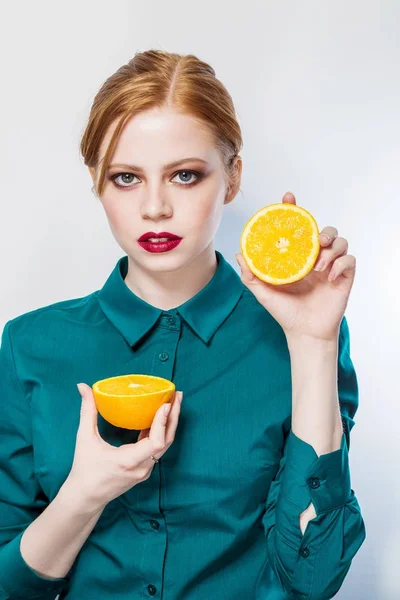 Wanita muda berambut merah seksi memegang buah jeruk setengah pada latar belakang putih . — Stok Foto