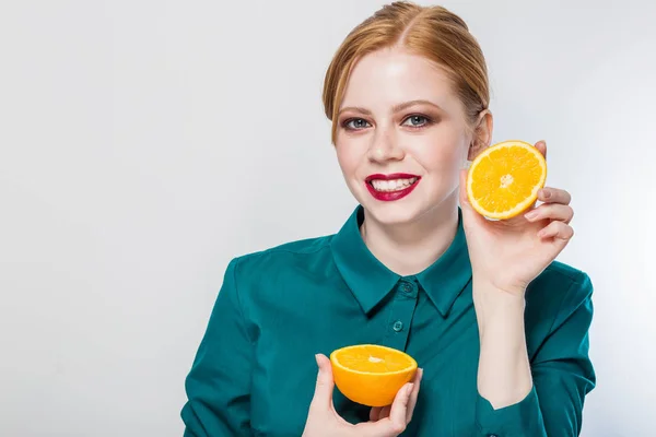 Wanita muda berambut merah yang ceria memegang jeruk di depan matanya. Konsep makan yang sehat. Diet. Terisolasi di atas putih . — Stok Foto