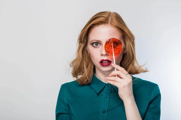 Hermosa mujer sorprendida con piruleta roja sobre fondo blanco — Foto de Stock