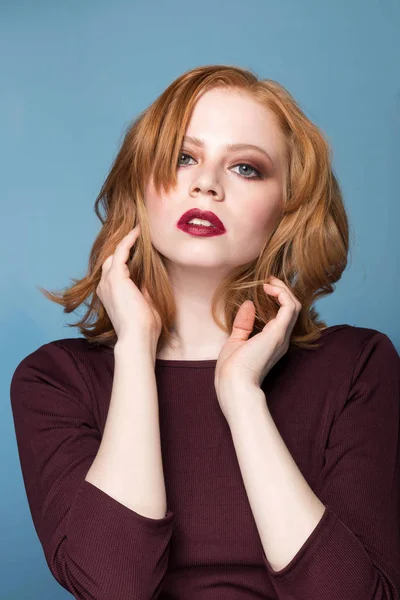 Portret van een roodharige meisje op blauwe achtergrond close-up. Mooie vrouw met professionele make-up, retoucheren. Mode, mode, cosmetica, emoties. — Stockfoto