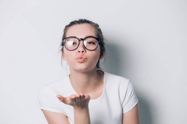 Sevimli güzel bayanı ayakta ve beyaz arka plan üzerinde öpücük gönderme yuvarlak güneş gözlüğü