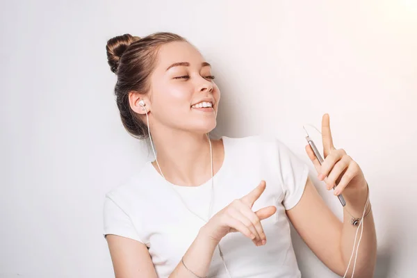 Hermosa mujer escuchando música en su teléfono a través de auriculares y baile . —  Fotos de Stock