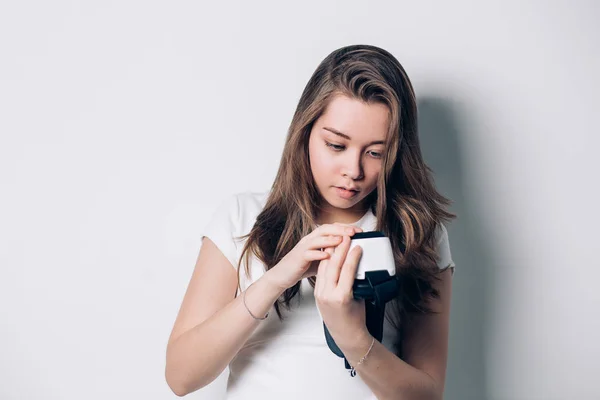 Bella ragazza in possesso di un auricolare realtà virtuale, mette il telefono, reso con un volto serio. tecnologia informatica — Foto Stock