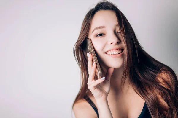 Hermosa mujer sonriendo hablando por teléfono inteligente sobre fondo blanco. Negociaciones, transacciones, tienda online . —  Fotos de Stock