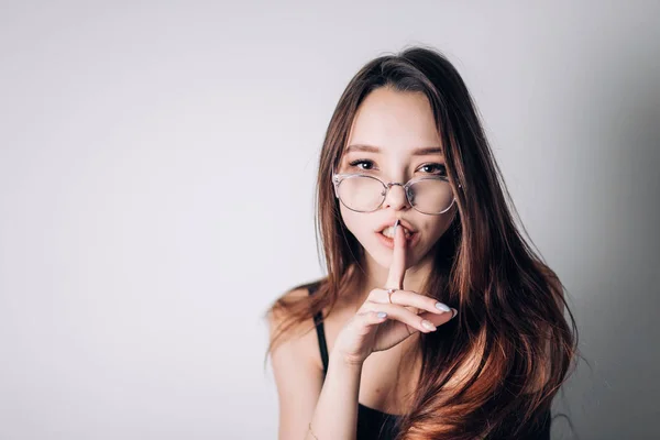 Attractive girl with natural face makeup In transparent glasses frame says it\'s a secret, Shh.