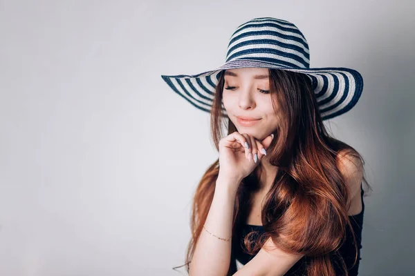 Beautiful woman in hat looking down with a smile on white background. Summer, holiday, sea, copy space. — Stock Photo, Image