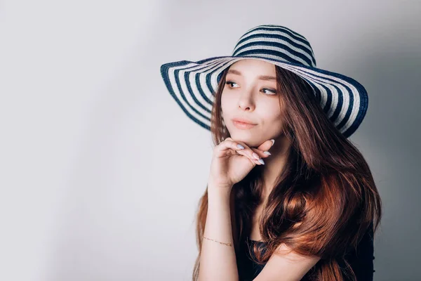 Hermosa mujer de moda en un sombrero mirando a un lado sobre un fondo blanco . —  Fotos de Stock