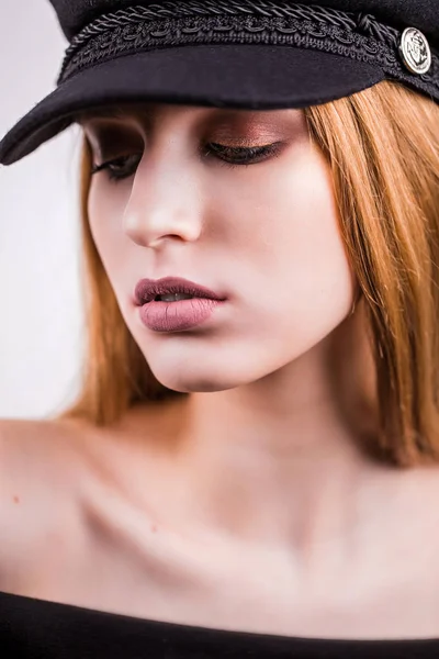 Close up of beautiful blonde woman with professional makeup looking down. Fashionable girl in a black cap — Stock Photo, Image