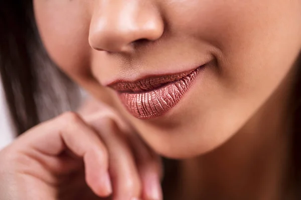 Primer plano de hermosas mujeres sonrientes de piel oscura, macro, disparo de detalle. Brillante lápiz labial marrón, brillo de labios, cosméticos, maquillaje . — Foto de Stock