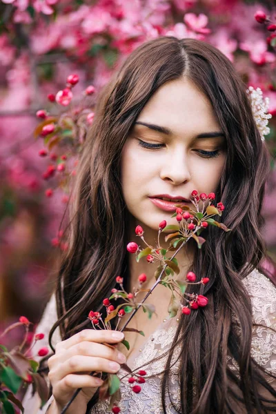 Portrait of beautiful girl in a pink dress, looking down with half open lips, keeps on hand a twig with buds, close-up — Stock Photo, Image