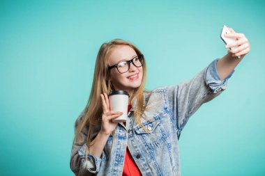 Selfie gülümseme ile mavi arka plan üzerine alarak güzel sarışın kız