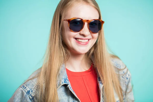 Retrato de una hermosa mujer rubia sobre fondo azul con gafas de sol — Foto de Stock