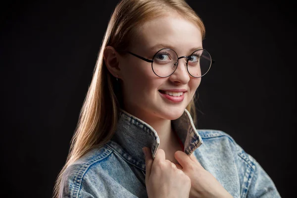Menina bonita com cabelo loiro e óculos redondos olhando com um sorriso para a câmera — Fotografia de Stock