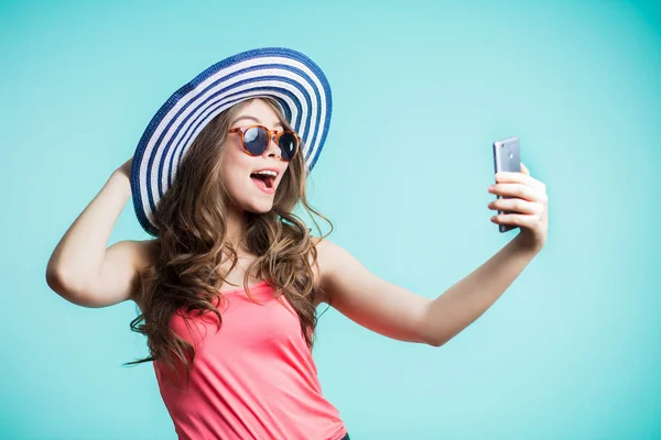 Szczęśliwa młoda kobieta, biorąc selfie na niebieskim tle. — Zdjęcie stockowe